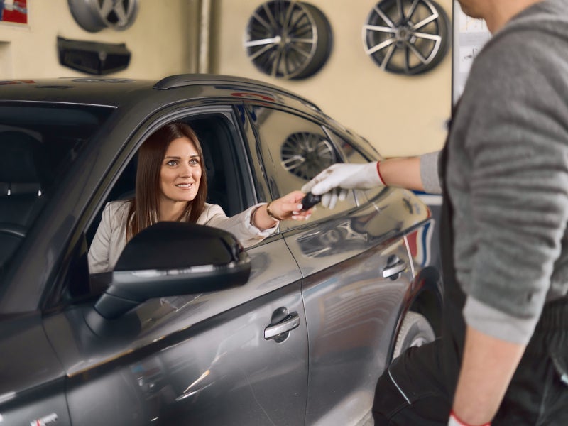 A woman hands a car key to a man, indicating a transfer of ownership or responsibility for the vehicle.